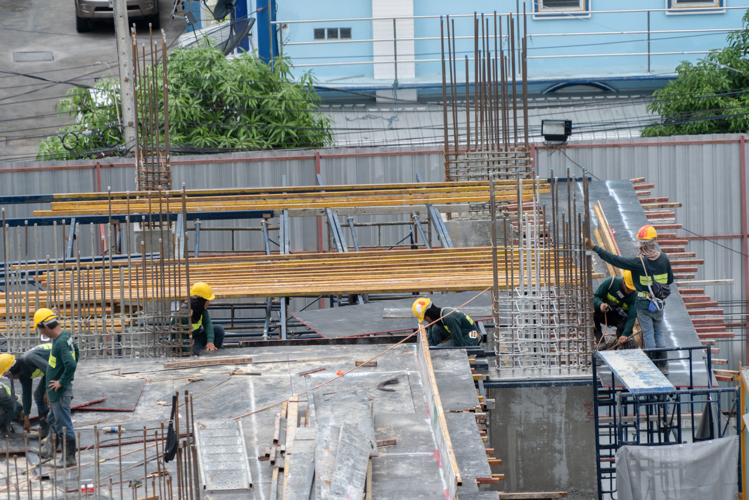 Aerial view of busy industrial construction site workers with cranes working. Top view of development high rise architecture building at noon. Hörhilfen für den Arbeitsplatz